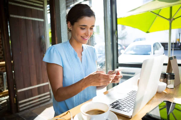 Female executive using mobile phone in cafe — Stock Photo, Image