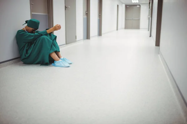 Tensed female surgeon sitting in corridor — Stock Photo, Image