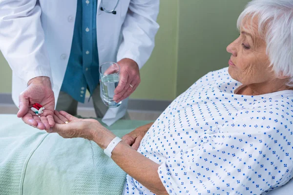 Doctor giving medicine pill to senior patient — Stock Photo, Image