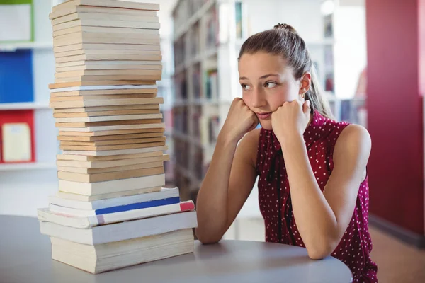 Triste colegiala mirando pila de libros — Foto de Stock