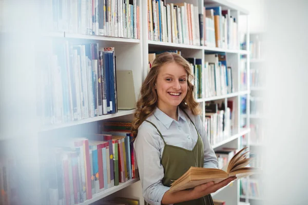 Schoolgirl reading book in library — Stock Photo, Image