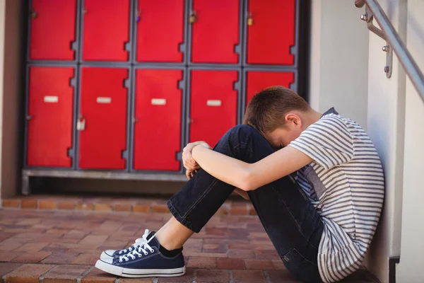 Sorgliga skolpojke sitter i korridoren — Stockfoto