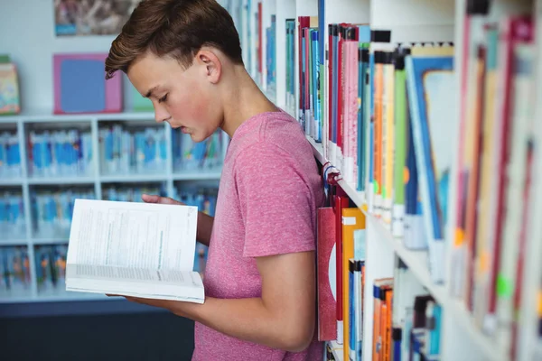 Estudante atento ler livro na biblioteca — Fotografia de Stock