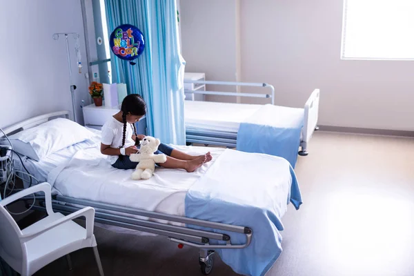 Yatakta oyuncak ayı ile oturan hasta — Stok fotoğraf