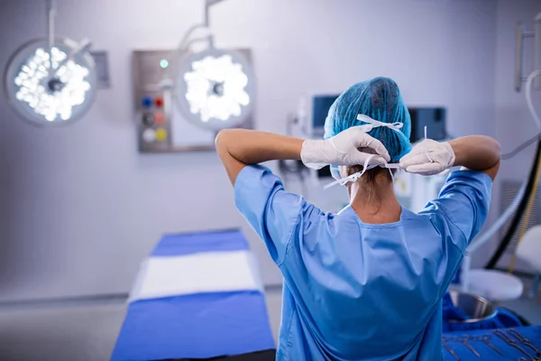 Vrouwelijke verpleegkundige gelijkmakende chirurgische masker — Stockfoto