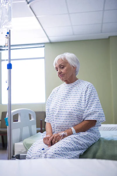 Besorgte Seniorin sitzt auf Bett — Stockfoto