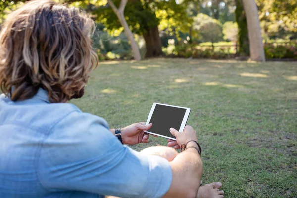 Hombre sentado en la hierba usando tableta — Foto de Stock