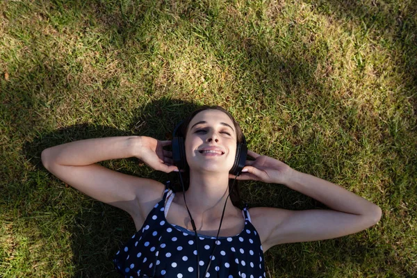 草の上に横たわると、音楽を聴く女性 — ストック写真