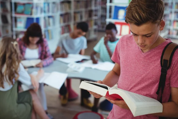 Schooljongen lezen boek met zijn klasgenoten — Stockfoto