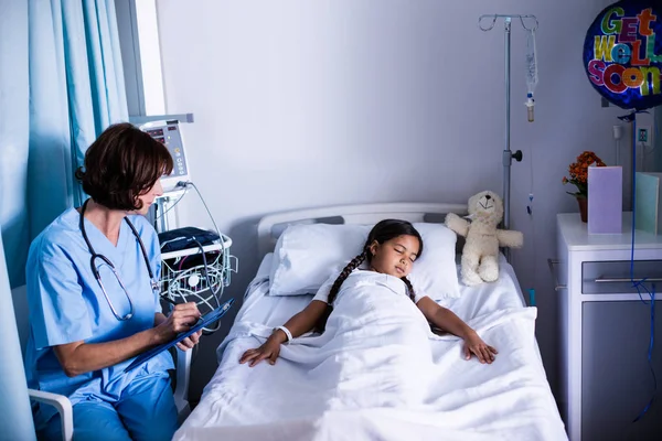 Doctor escribiendo en el portapapeles mientras mira al paciente —  Fotos de Stock