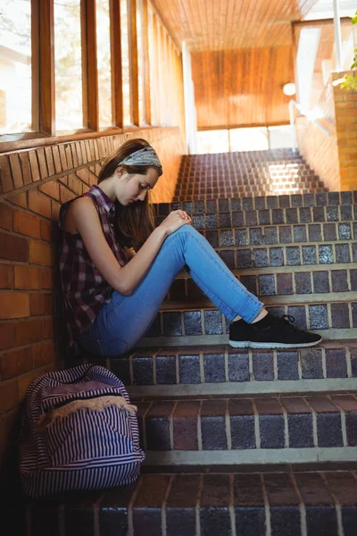Gadis sekolah yang sedih duduk sendirian di tangga — Stok Foto
