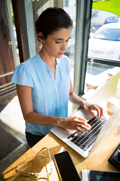 Vrouwelijke uitvoerend bezig met laptop in café — Stockfoto