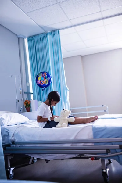 Patient sitting on bed with teddy bear — Stock Photo, Image