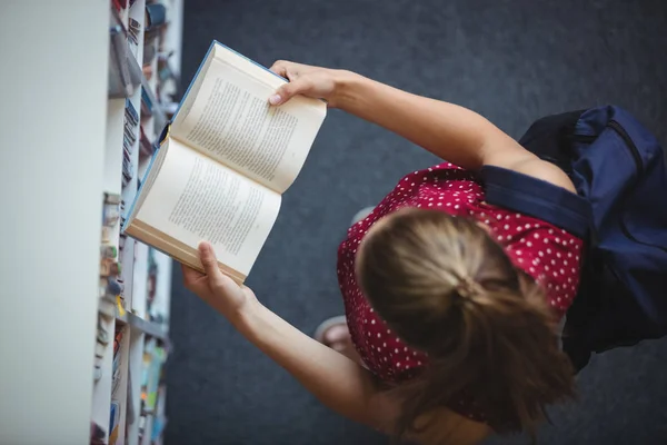 Attentif écolière lecture livre dans la bibliothèque — Photo