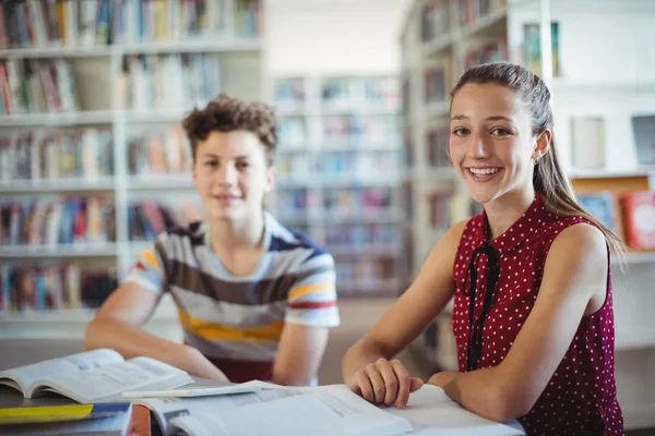 Школьница, сидящая со своим одноклассником в библиотеке — стоковое фото