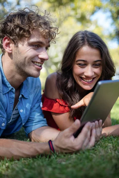 Paar auf Gras liegend und mit Tablet — Stockfoto