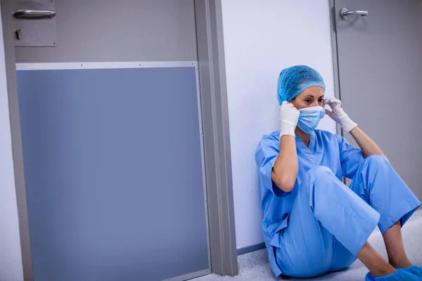 Sorgliga kirurg sitter på golvet i korridoren — Stockfoto