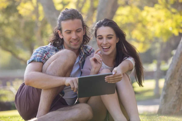 Casal sentado na grama e usando tablet — Fotografia de Stock