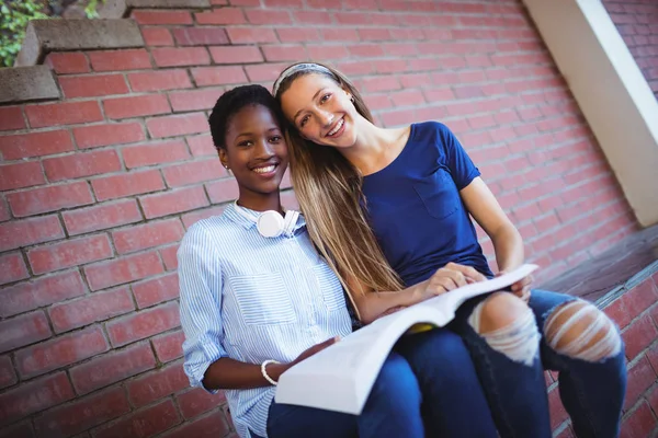 Porträtt av glad skolflickor läser bok — Stockfoto