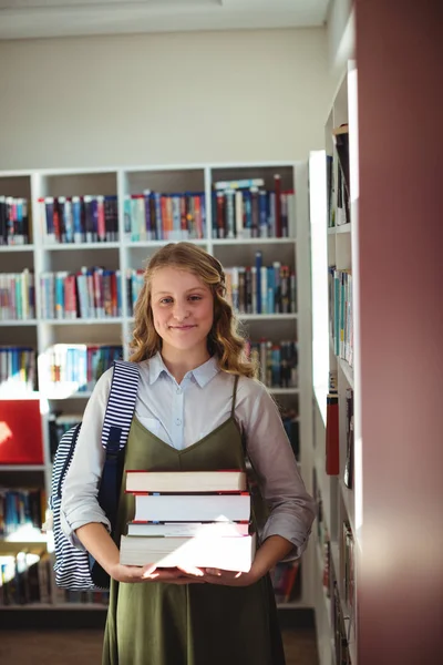 Scolaretta in piedi con pila di libri — Foto Stock