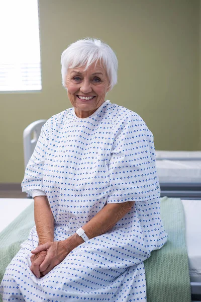 Smiling senior patient sitting on bed in hospital — Stock Photo, Image