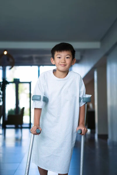 Boy patient walking with crutches in corridor — Stock Photo, Image