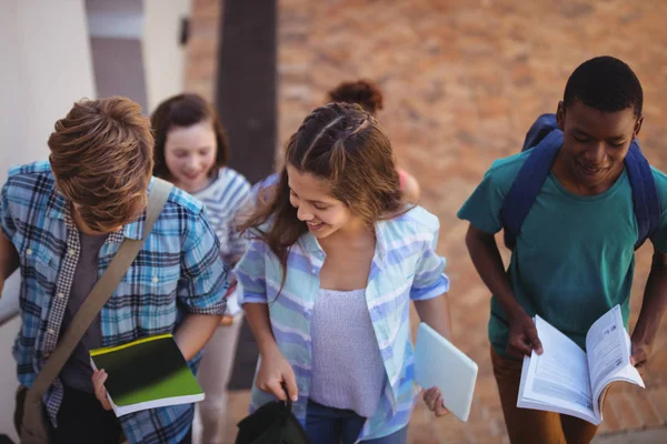 Estudantes segurando livros e tablet caminhando — Fotografia de Stock