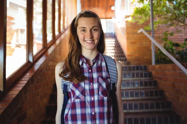 Schoolgirl to schoolbag standing near staircase — Stock Photo, Image