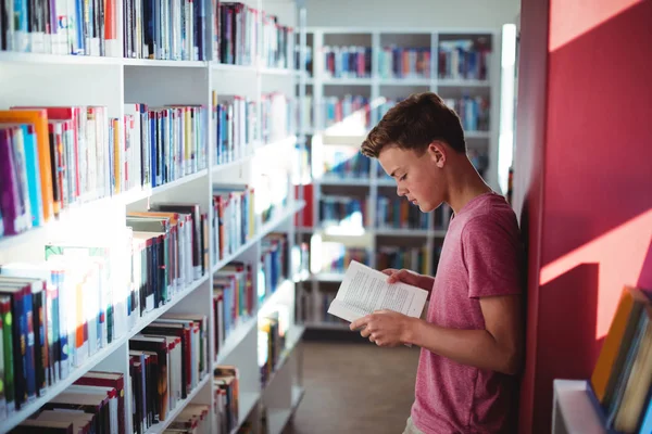 Schoolboy livro de leitura na biblioteca — Fotografia de Stock