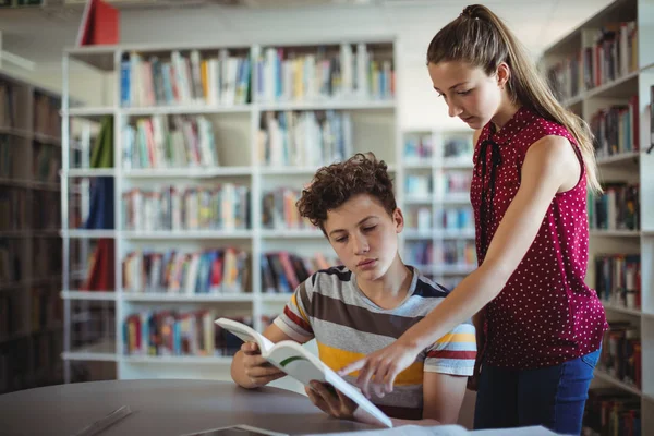 Klasskamrater läser bok i biblioteket — Stockfoto