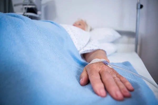 Senior patient hand with saline on bed — Stock Photo, Image