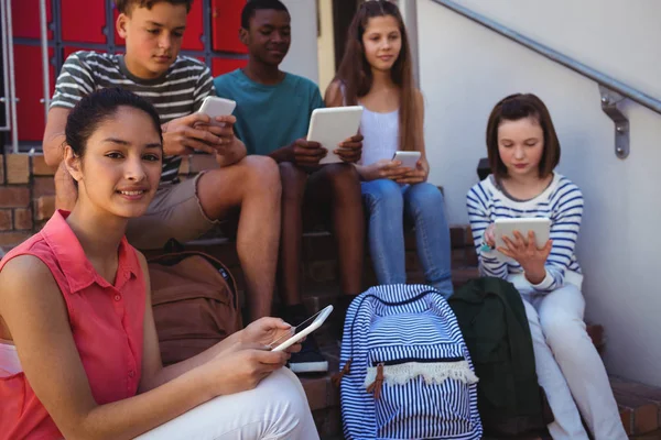 Telefon ve tablet merdiven üzerinde kullanan öğrenciler — Stok fotoğraf