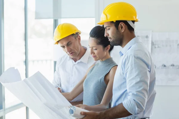 Three architects discussing over blueprint — Stock Photo, Image