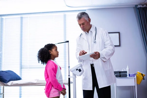 Médico usando tablet enquanto mede a altura da menina — Fotografia de Stock