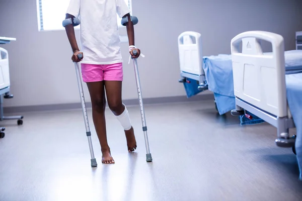 Menina andando com muletas na enfermaria — Fotografia de Stock