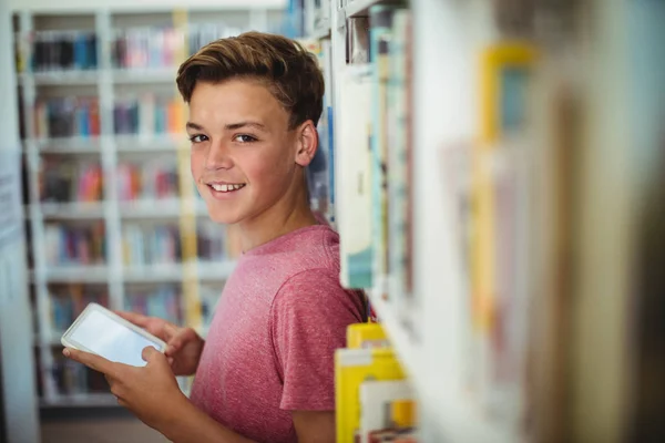 Schooljongen holding digitale tablet in bibliotheek — Stockfoto