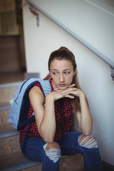 Sad schoolgirl sitting alone on staircase — Stock Photo, Image