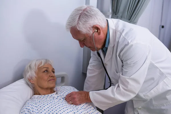 Médico examinando paciente sênior com estetoscópio — Fotografia de Stock