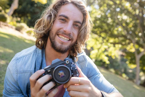 Homme assis dans le parc avec appareil photo numérique — Photo