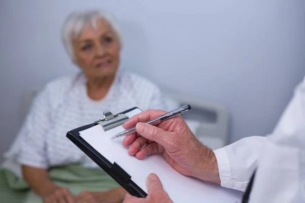 Arzt diskutiert Arztbericht mit Seniorin — Stockfoto