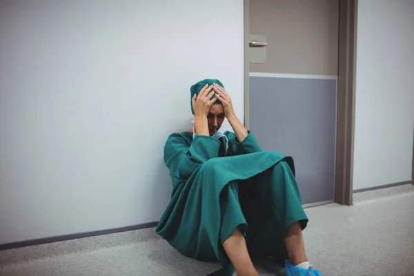 Напряженная женщина-хирург сидит в коридоре — стоковое фото