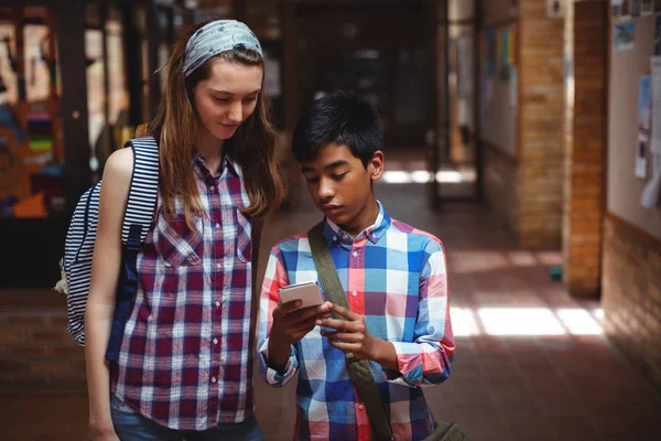 Spolužáci, používající mobilní telefon v chodbě — Stock fotografie