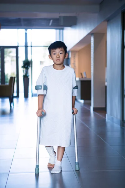 Chłopiec pacjenta spaceru z kulami w korytarzu — Zdjęcie stockowe