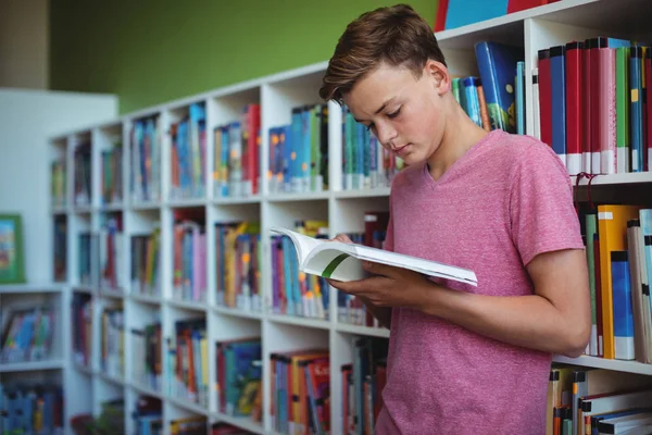 Uważny uczniak czytania książki w bibliotece — Zdjęcie stockowe