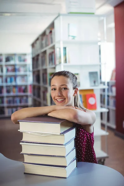 Écolière penché de livres empilés — Photo