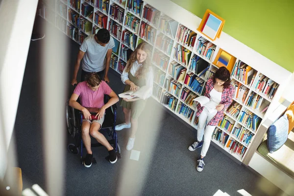 Étudiants interagissant les uns avec les autres dans la bibliothèque — Photo