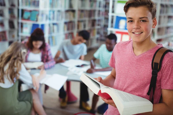 Schooljongen bedrijf boek met klasgenoten — Stockfoto