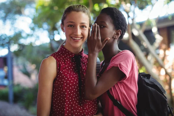 Écolière chuchotant dans son oreille amis — Photo