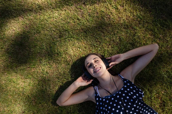 Donna sdraiata sull'erba e ascoltare musica — Foto Stock