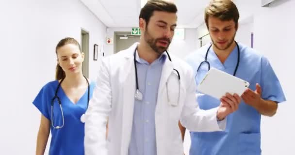 Команда врачей взаимодействует во время прогулки по коридору — стоковое видео